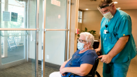 Patient in wheelchair getting transported by healthcare provider.